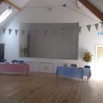 Tables set up for an event in Ashurst Village Hall which is decorated with bunting